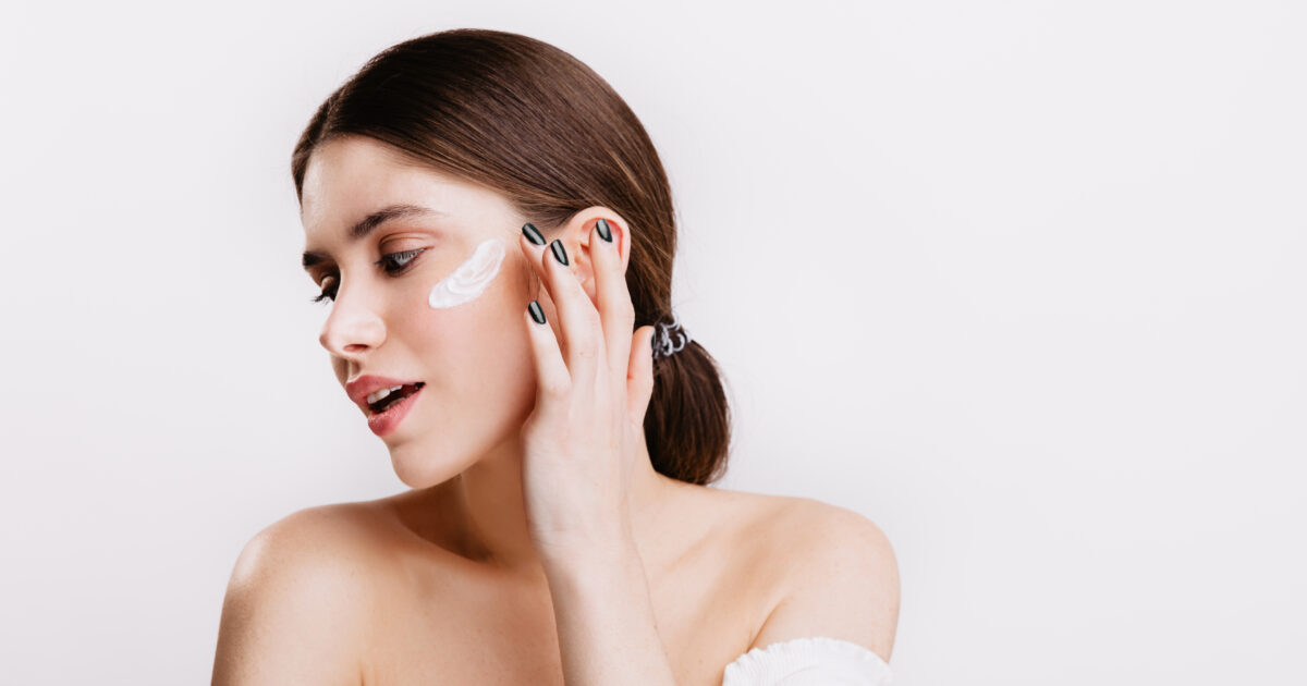 image-dark-haired-lady-without-makeup-puts-moisturizer-on-her-face-girl-with-black-manicure-gently-touches-skin